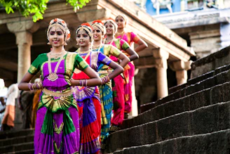 Five dancers in colorful traditional indian attire on steps