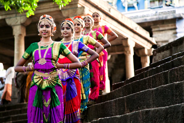 Five dancers in colorful traditional indian attire on steps