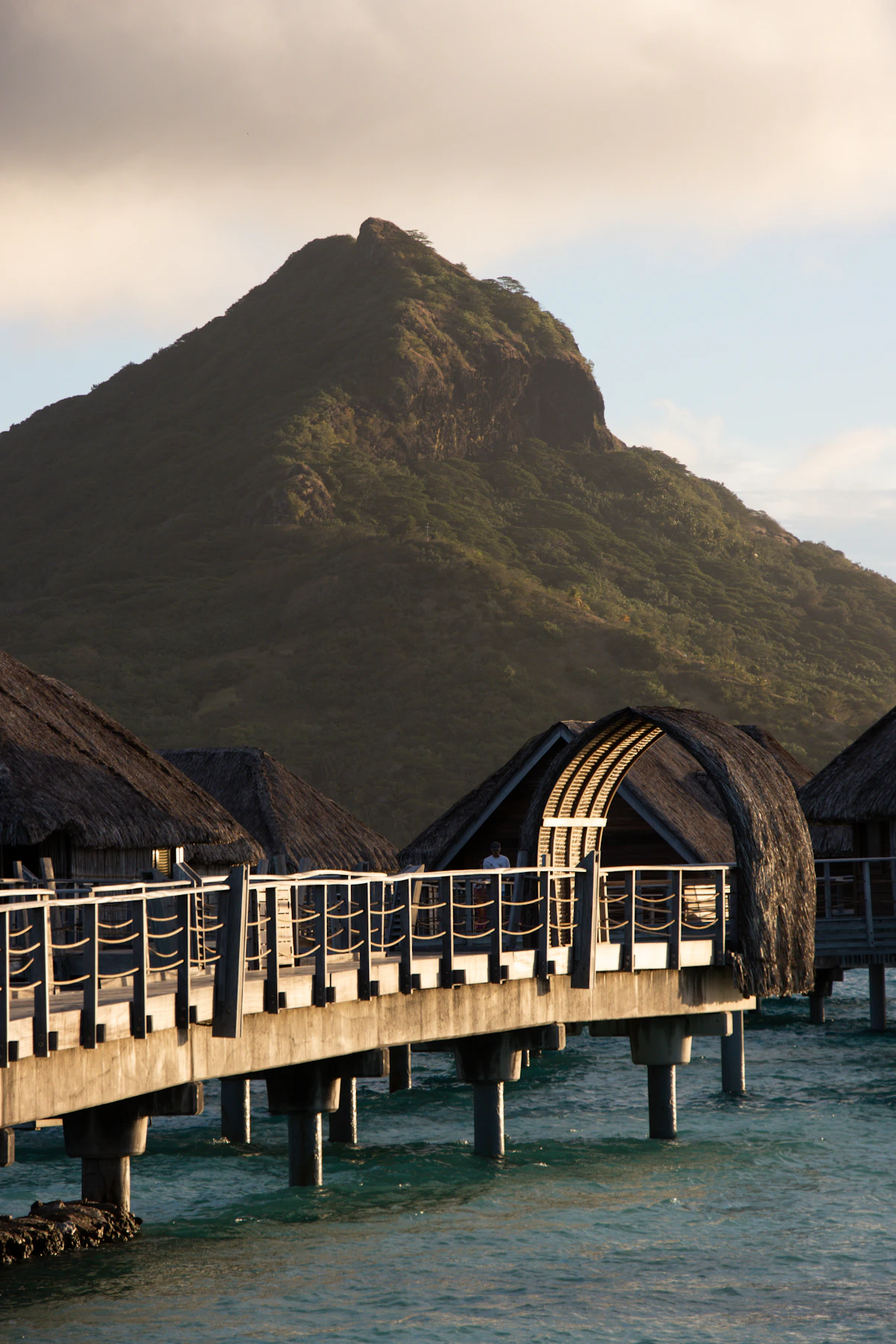 Overwater thatched bungalows on a turquoise lagoon in Bora Bora, French Polynesia, with Mount Otemanu in the distance