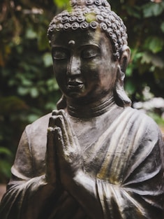 A serene buddha statue with hands clasped in prayer.