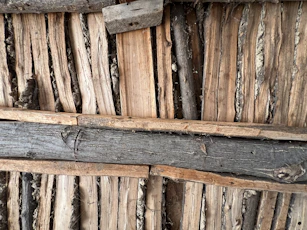 Rough wooden planks and logs form a rustic wall