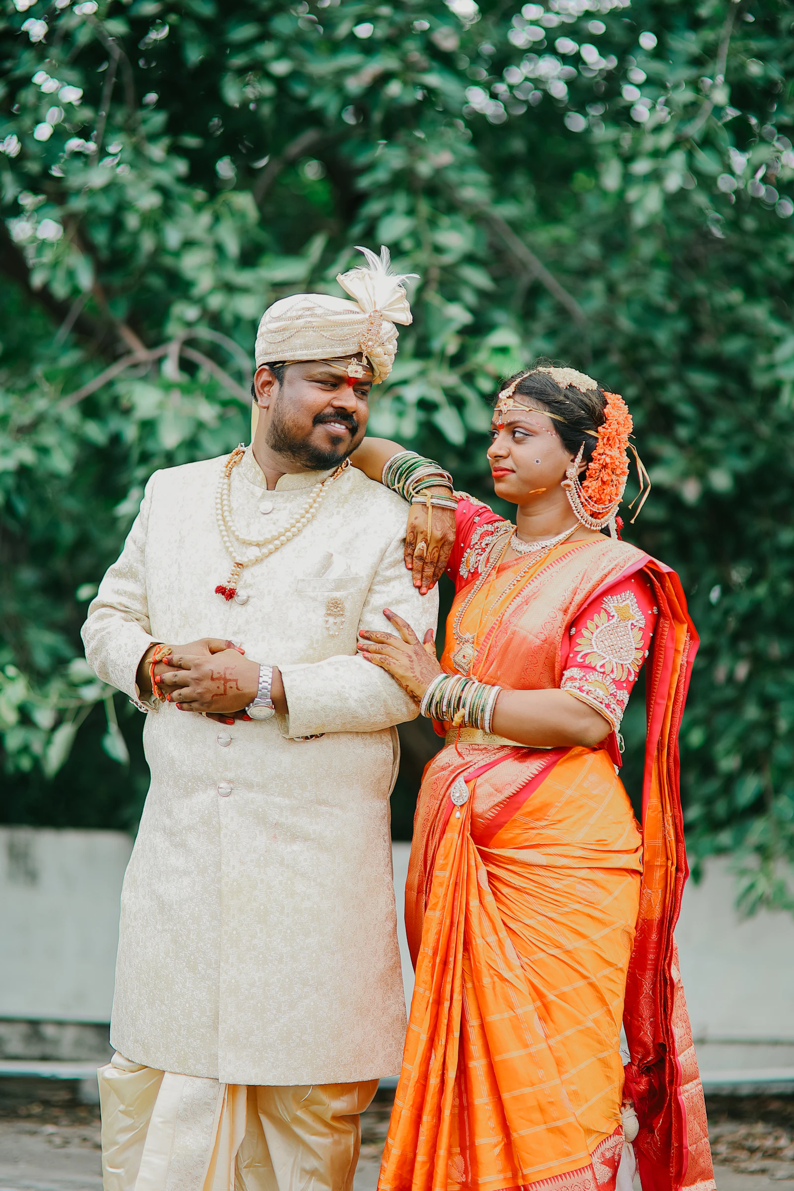 Indian wedding couple wearing a silk saree and traditional groom attire outdoors