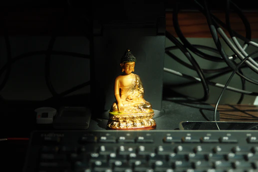 Golden buddha statue on a desk with keyboard.