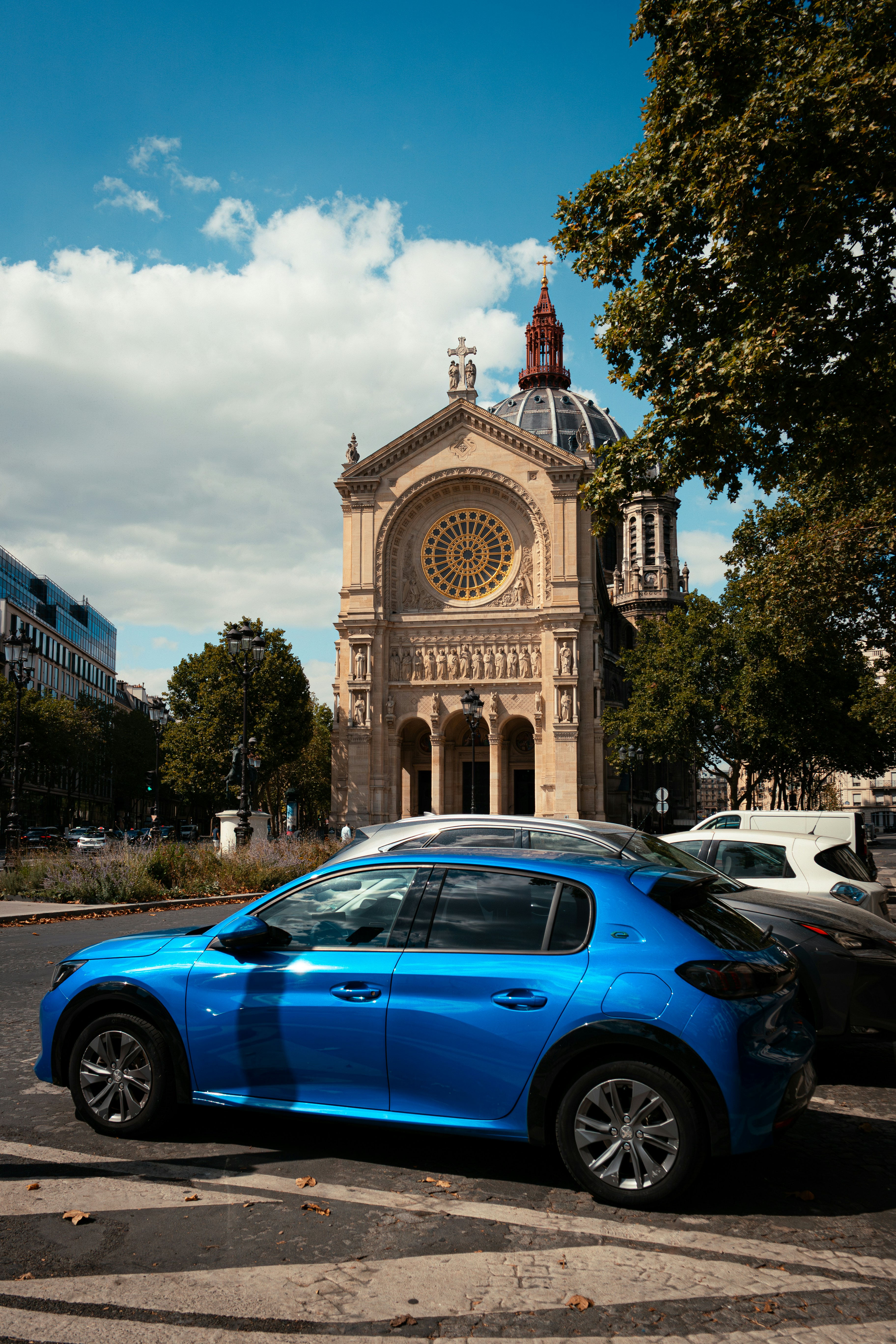 Carro azul estacionado perto de uma grande igreja ornamentada.