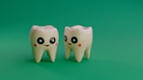 Two cartoon teeth smiling on a green background