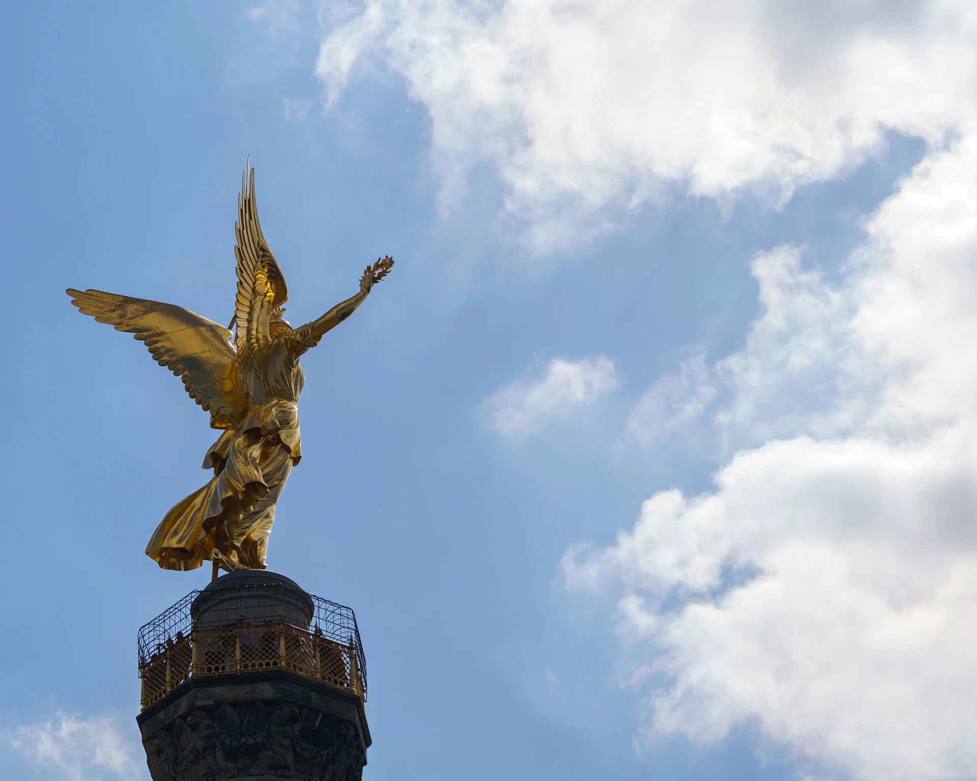 Golden angel statue against a cloudy blue sky