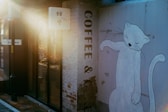 White cat mural on building with "coffee &" text.