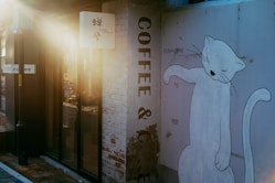 White cat mural on building with "coffee &" text.