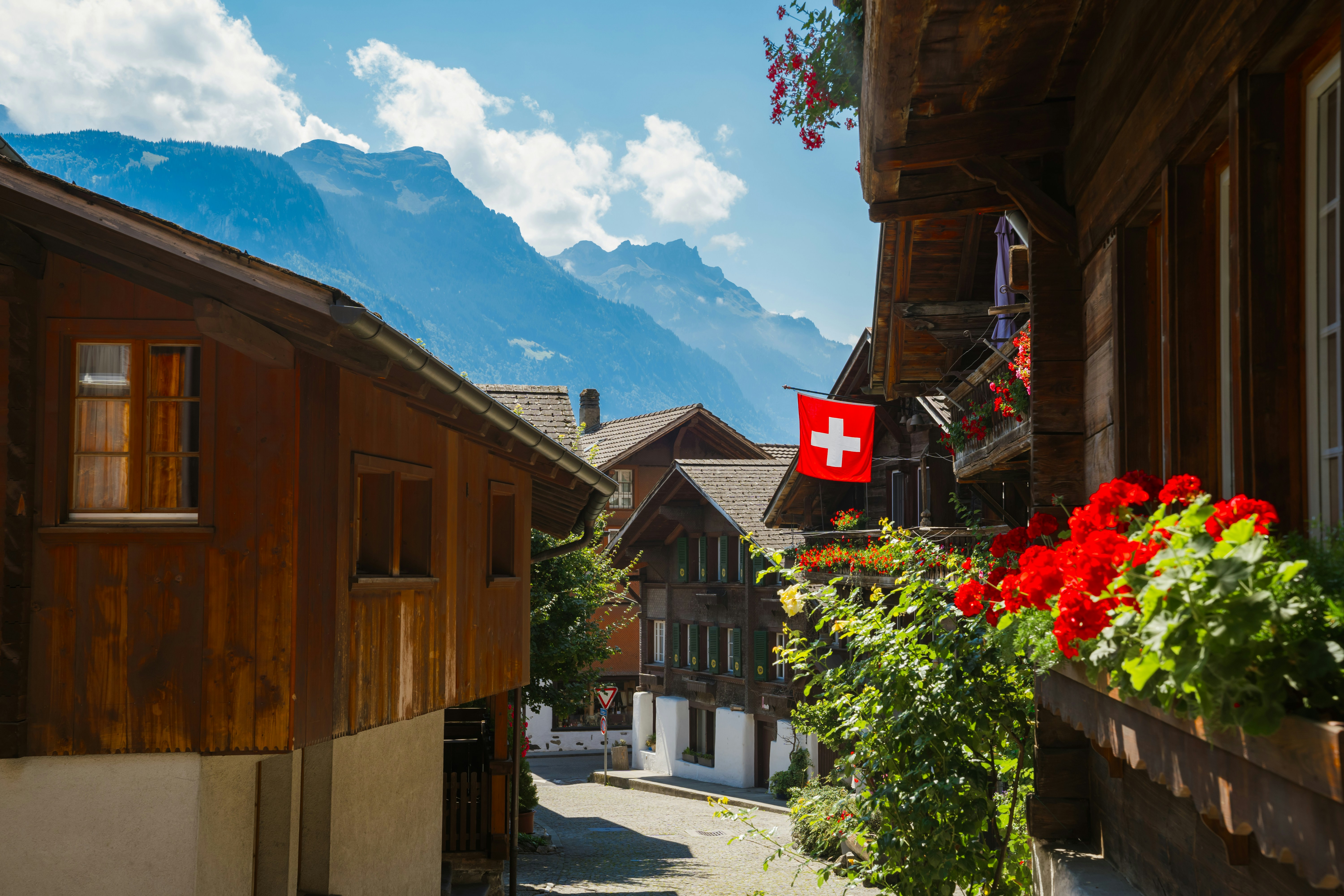 Swiss village street with mountains and swiss flag.
