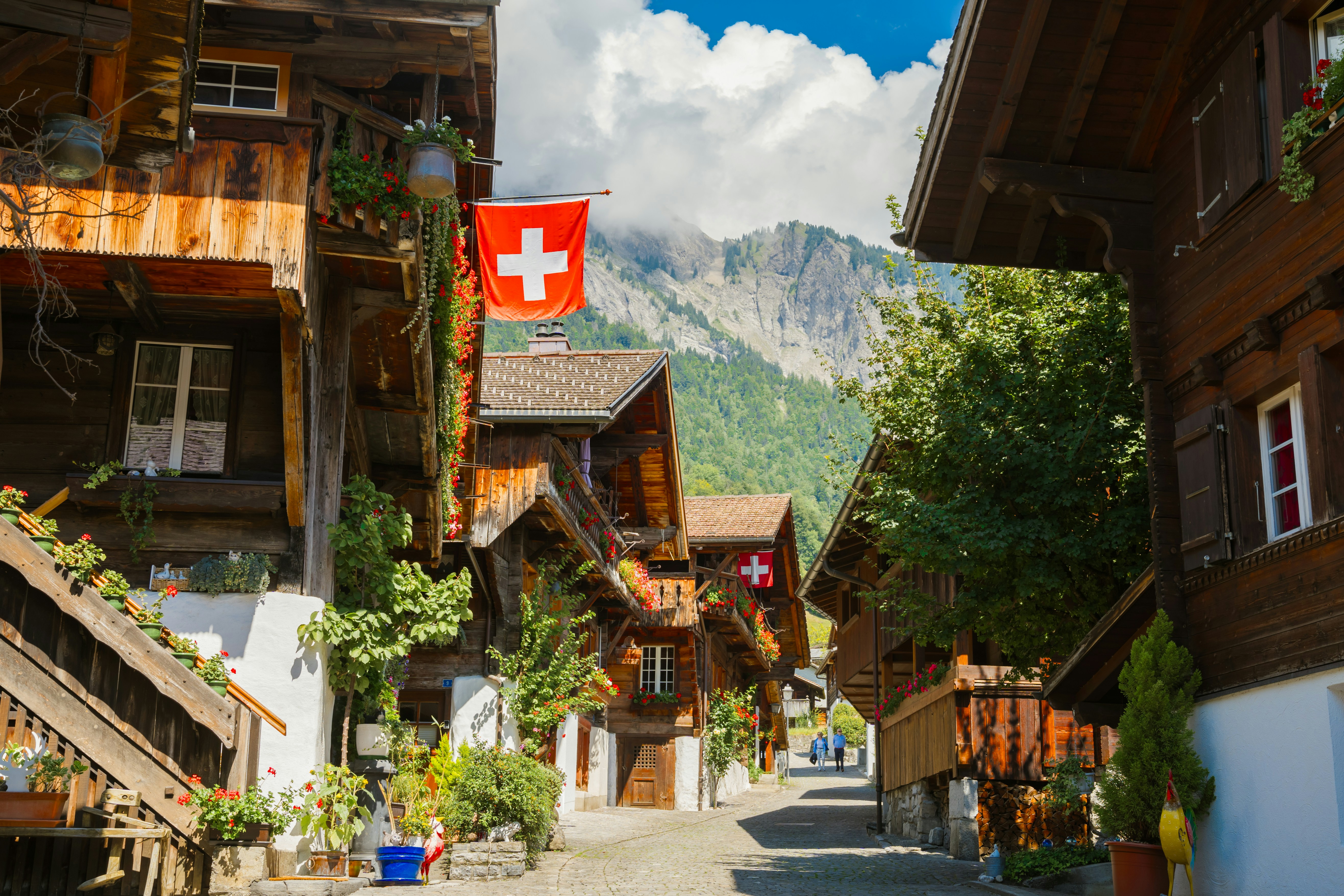 Swiss flag flies over a village with wooden houses.