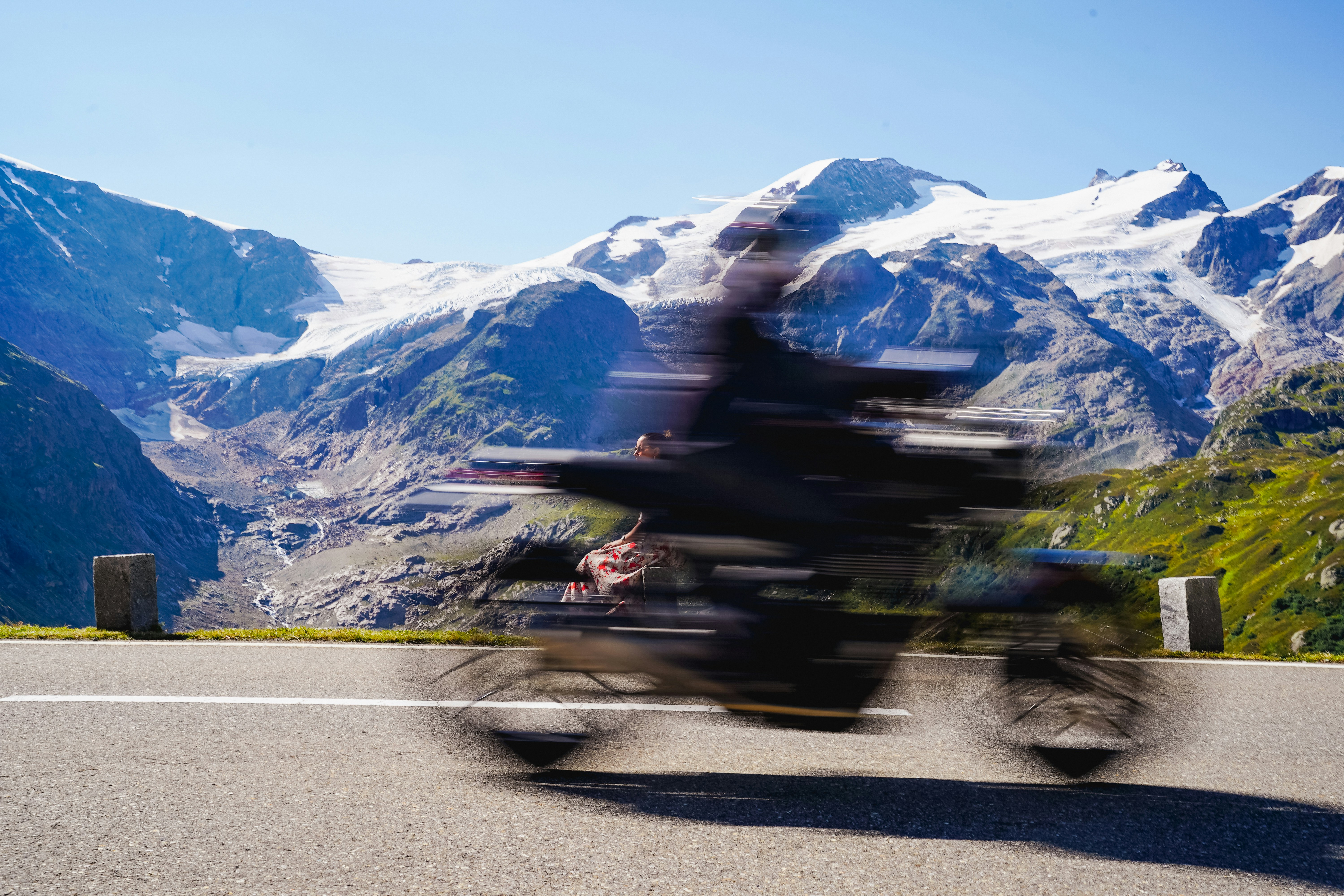 Motorcycle speeding past snowy mountains on a sunny day