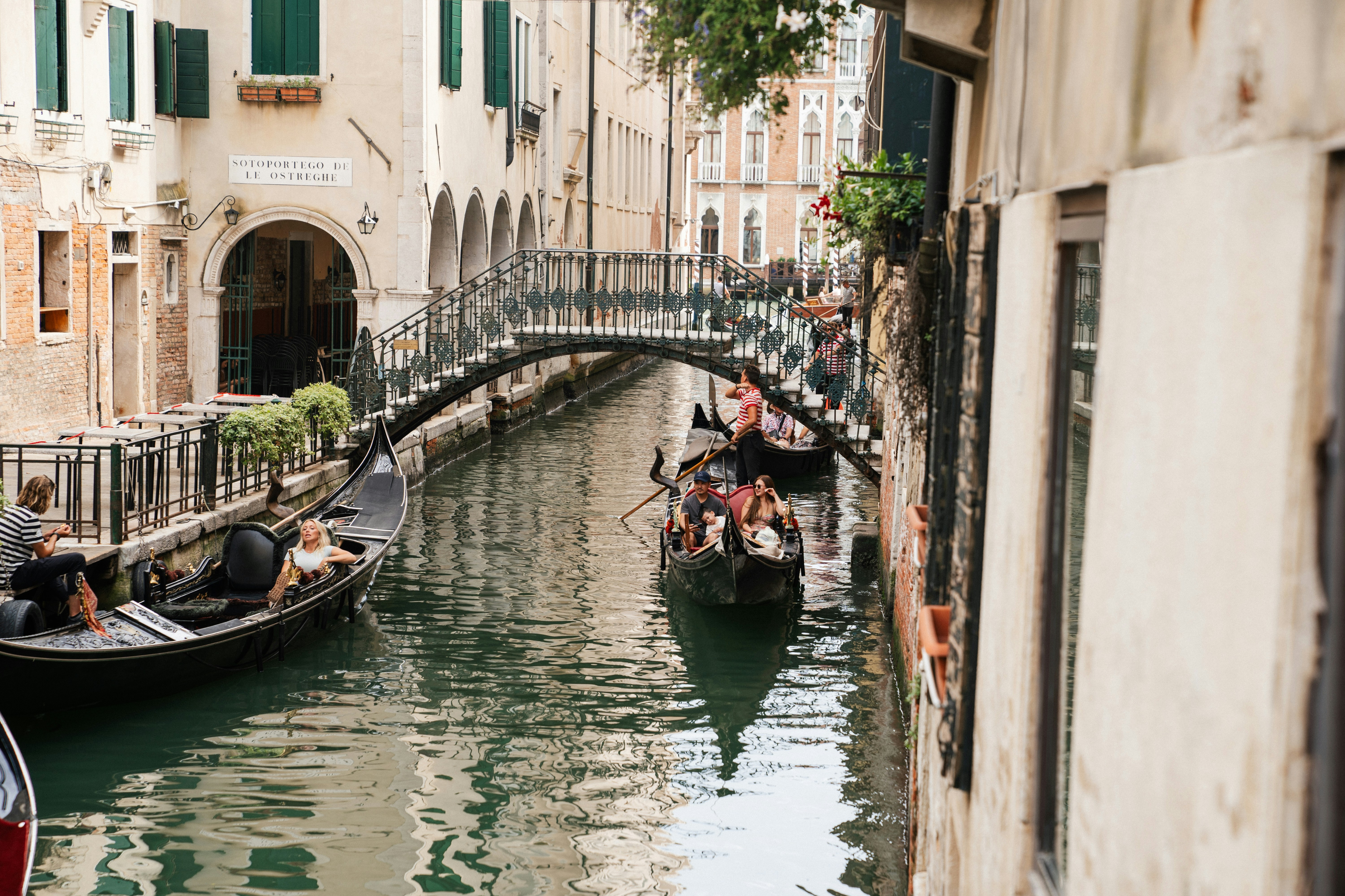 Gondolas navigate a narrow canal in venice, italy.