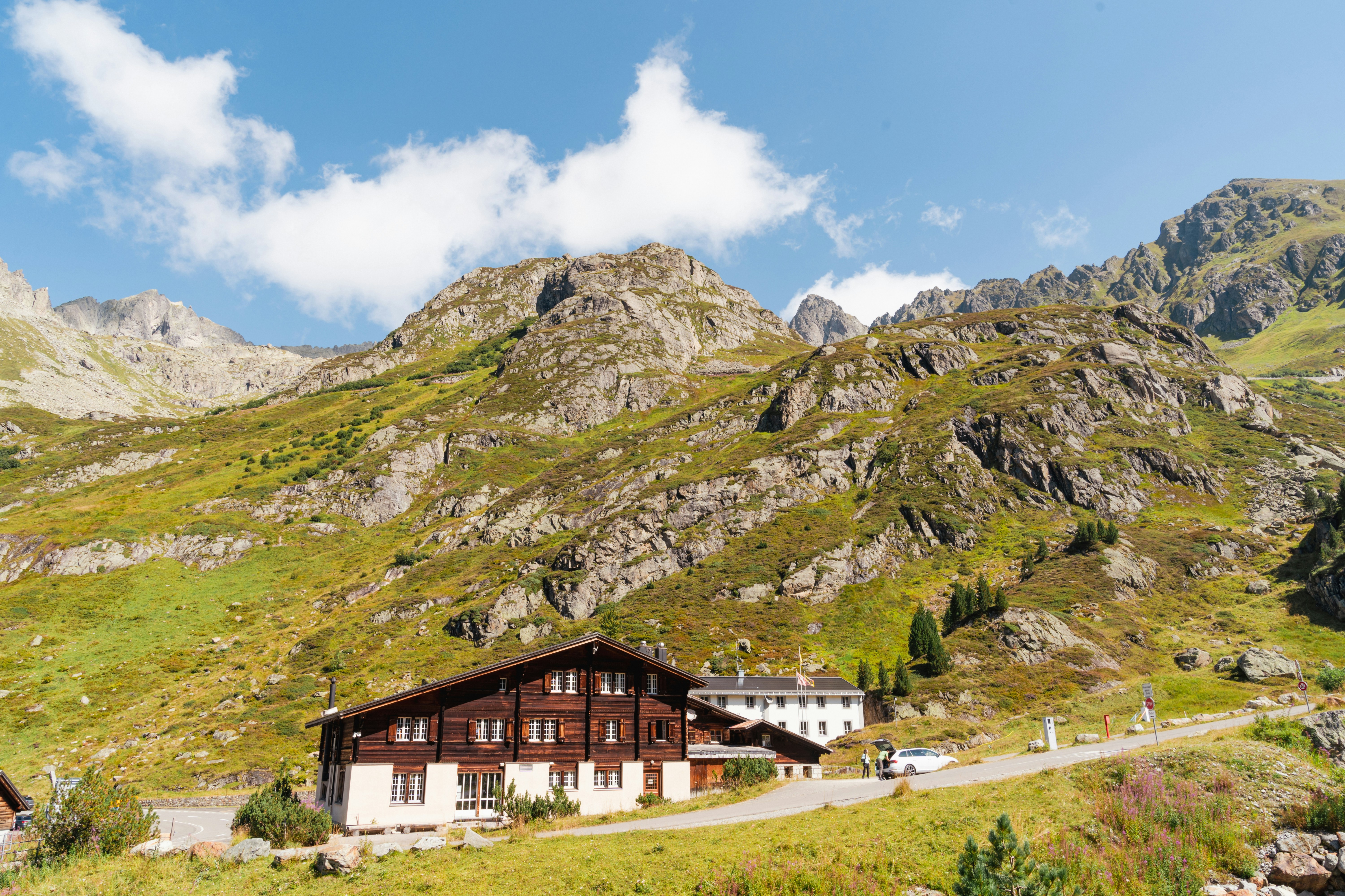 Wooden lodge nestled in a grassy mountain landscape.