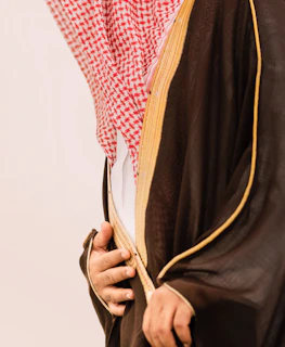 Man in traditional saudi clothing with red and white headdress.
