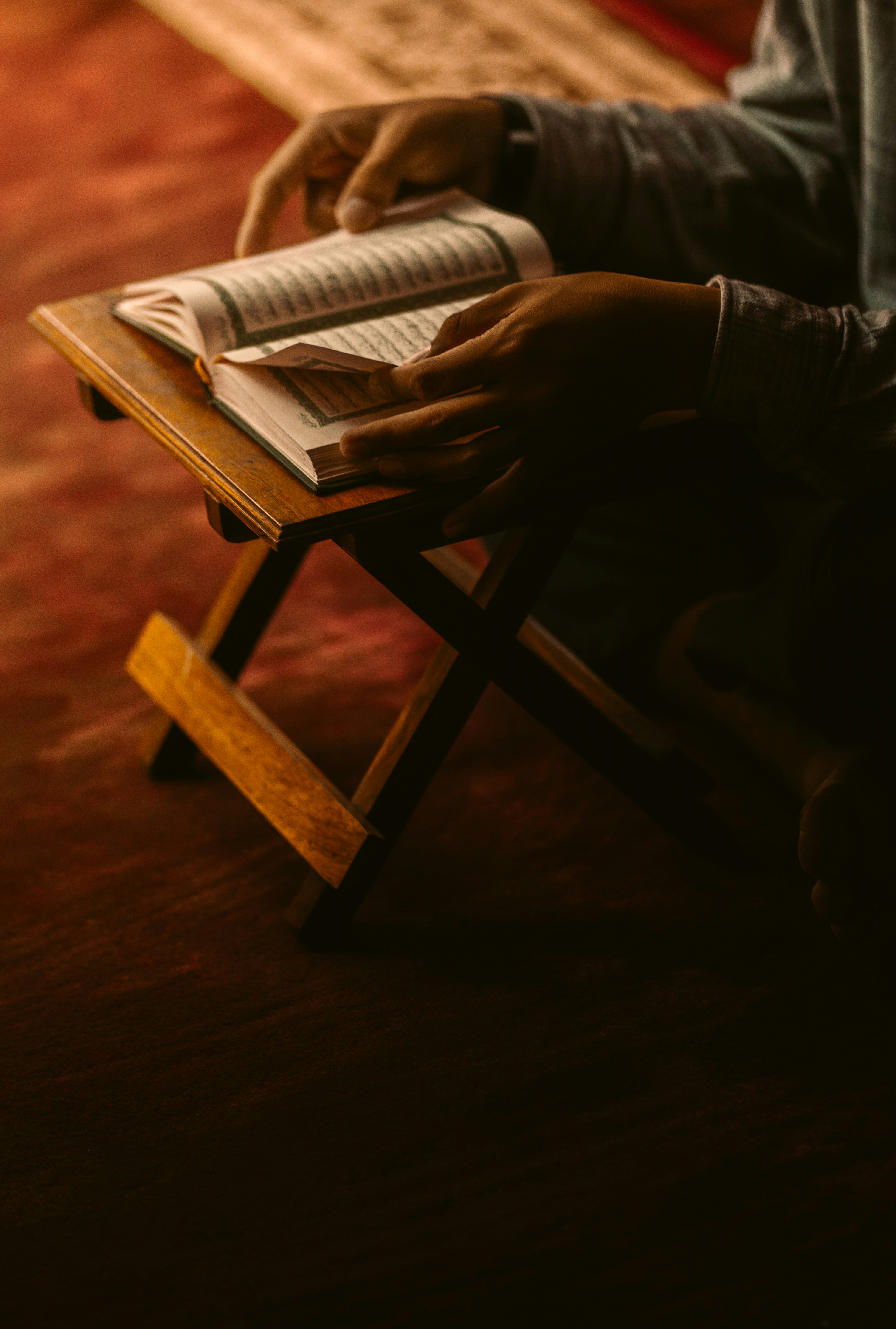 Person reading a book on a wooden stand