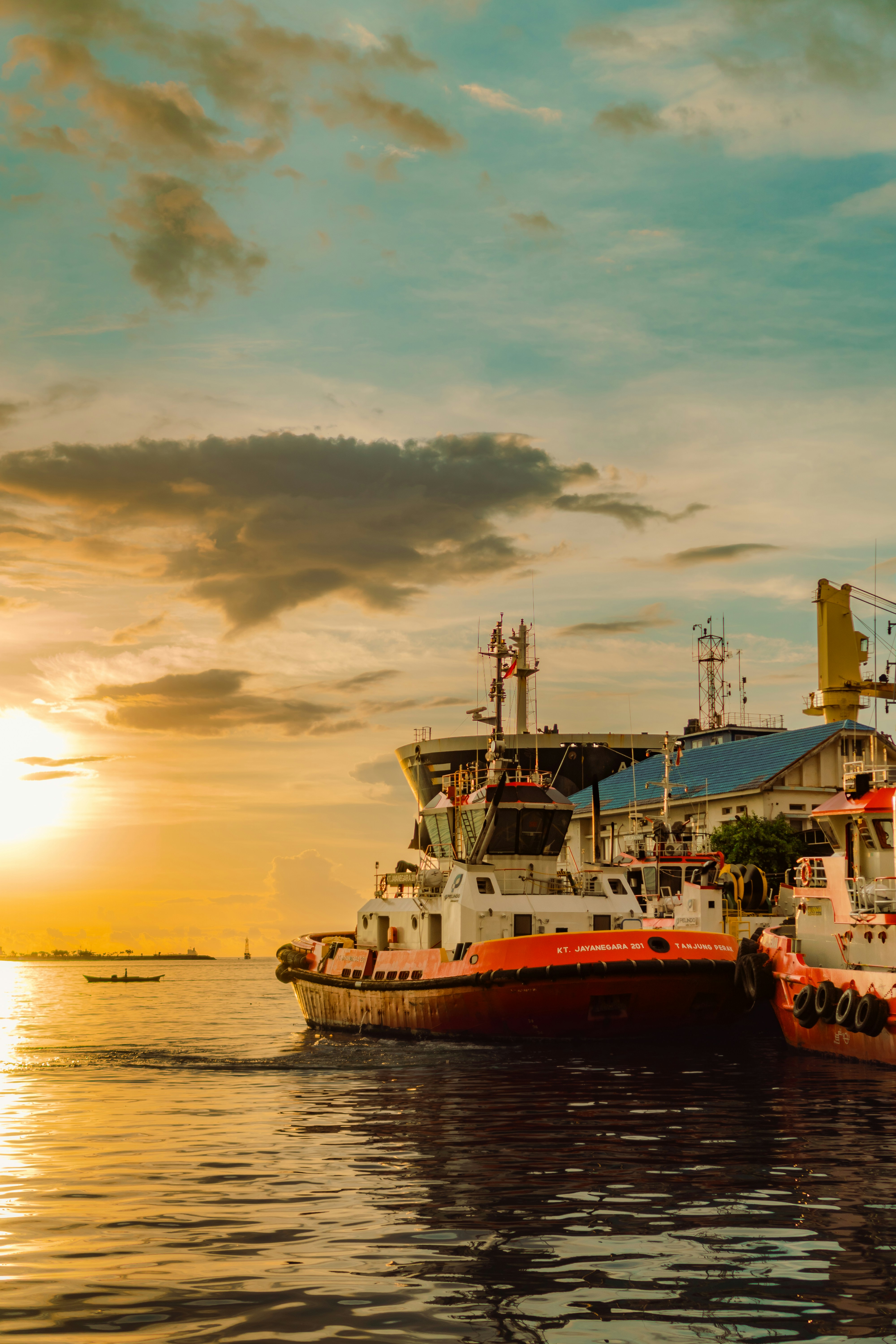 Tugboats docked in harbor at sunset