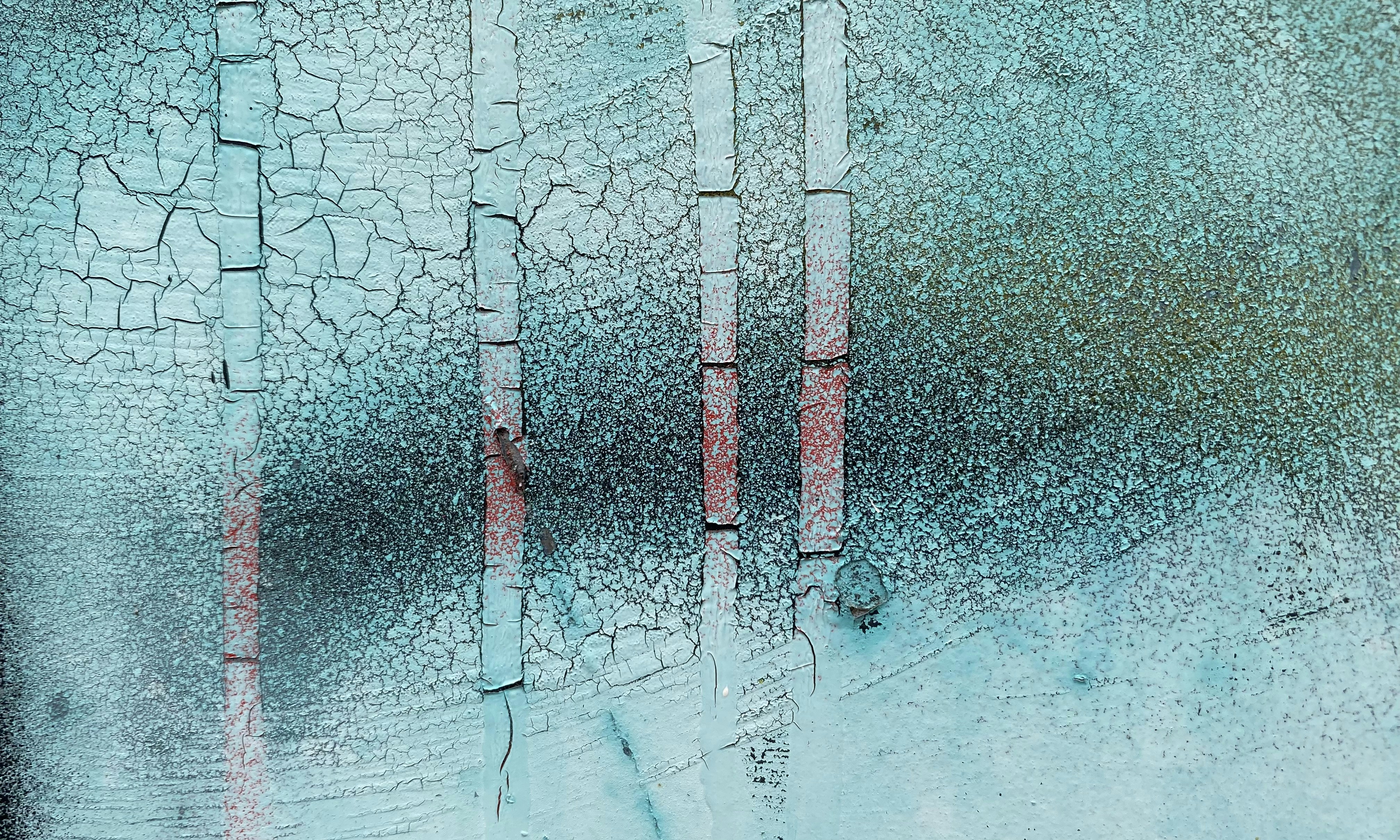 Cracked teal paint with red spray paint lines.