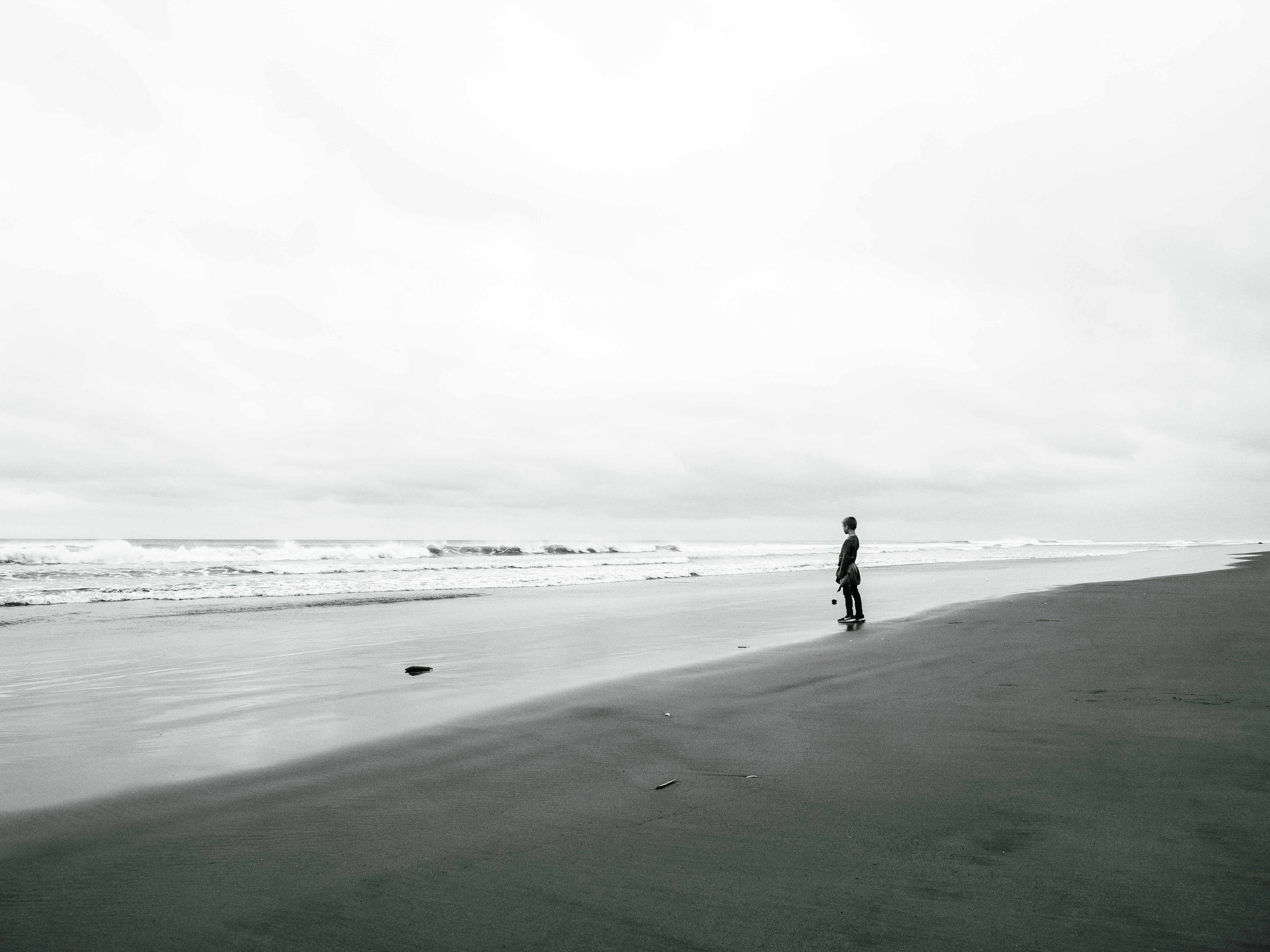 Person standing on a sandy beach by the ocean.