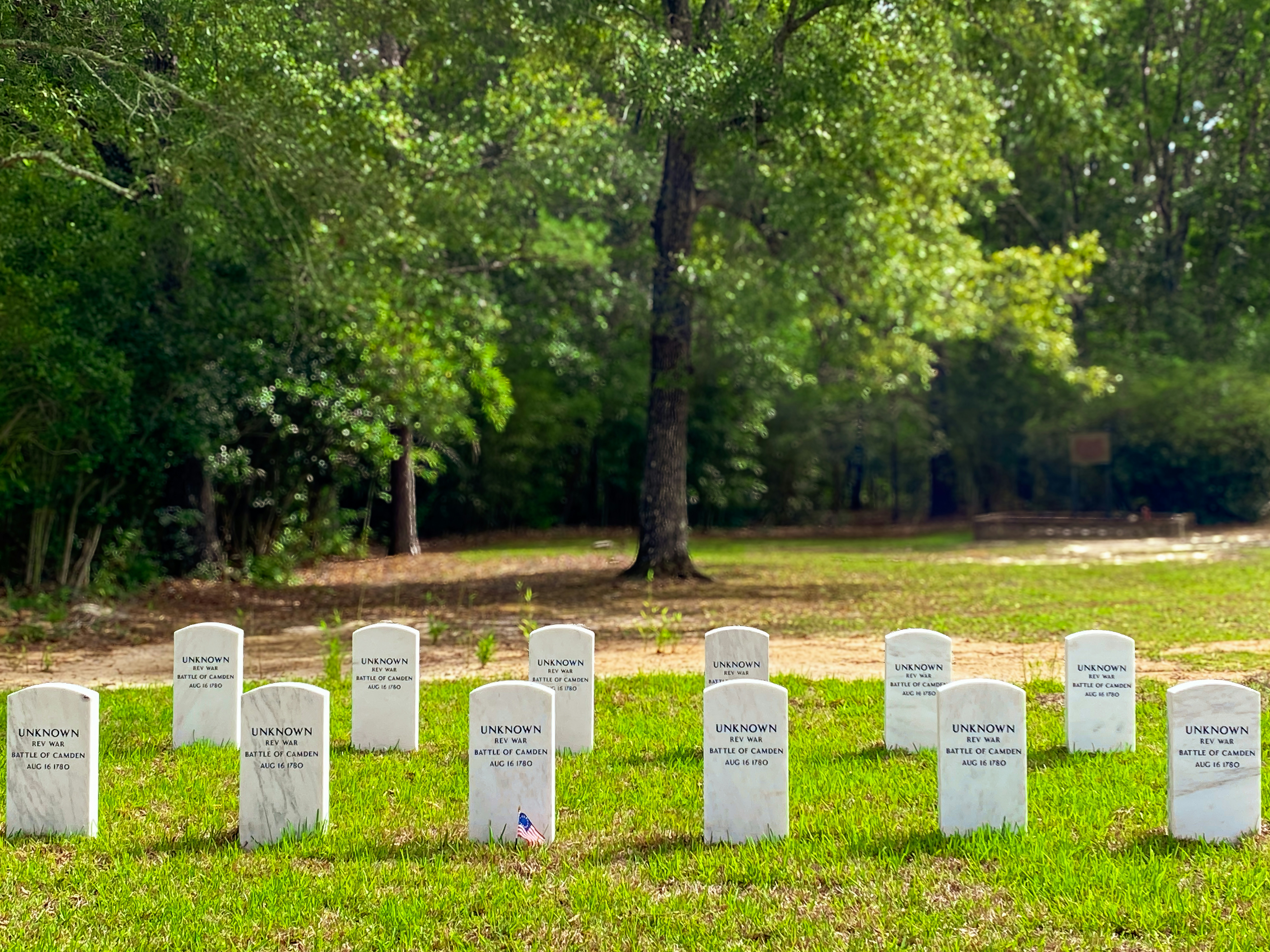 Rows of white gravestones in a grassy field.