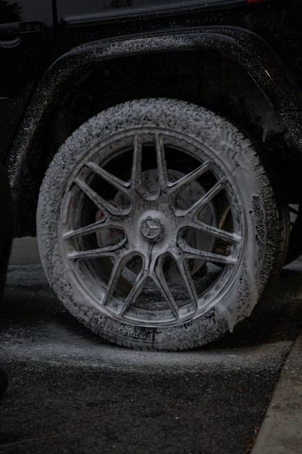 Close-up of a car wheel covered in white foam.