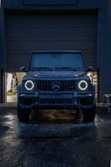 A dark suv with glowing headlights at night.