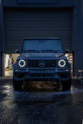 A dark suv with glowing headlights at night.