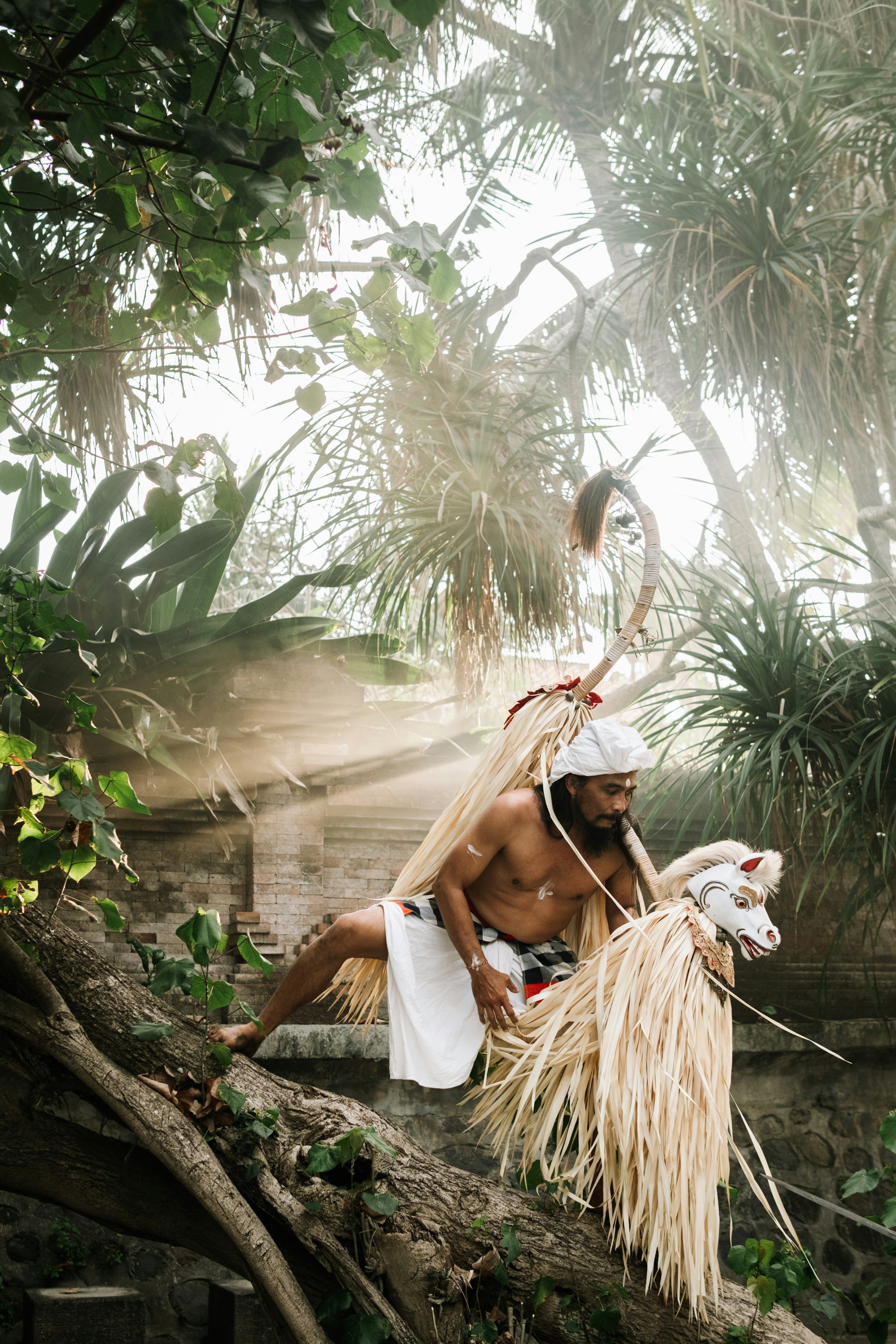 Hombre en traje tradicional con máscara de caballo en un entorno tropical