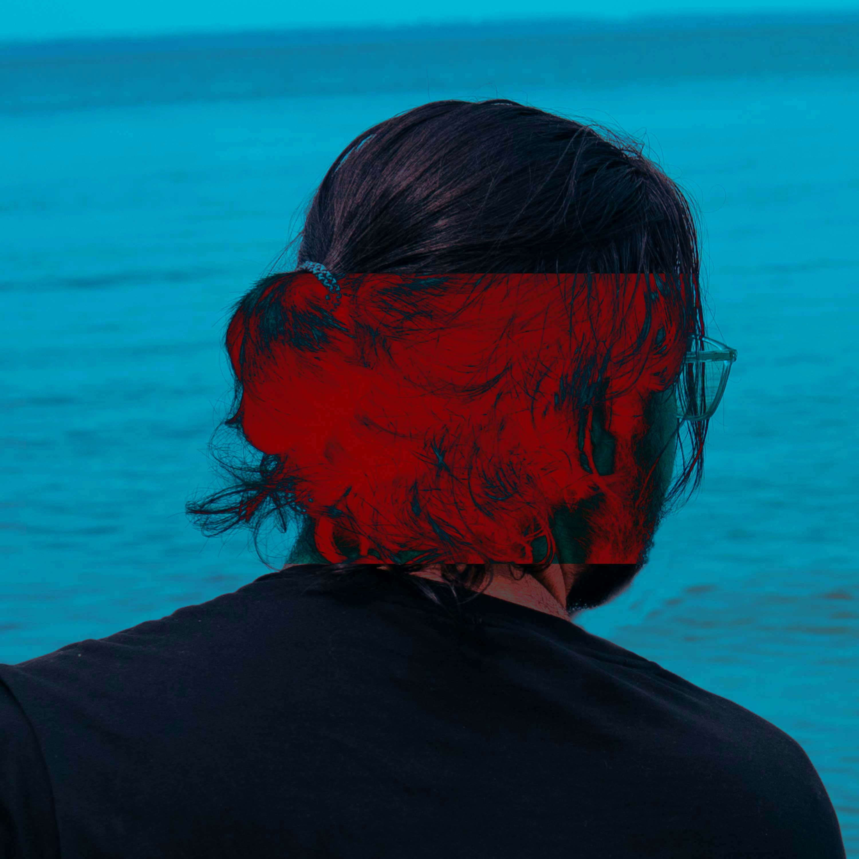 Man with red glitch effect on hair by the ocean