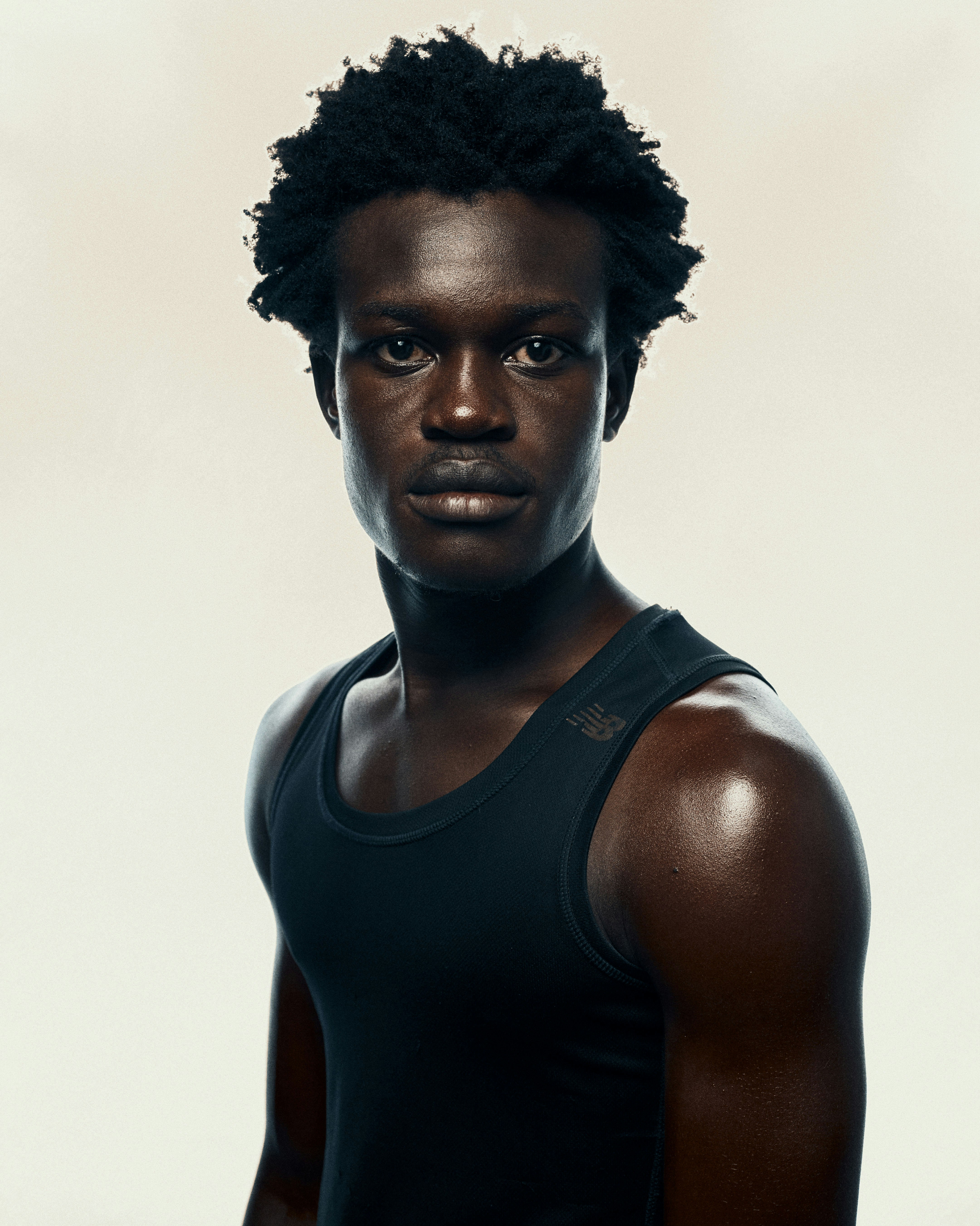 Young man with dark skin and curly hair wearing tank top