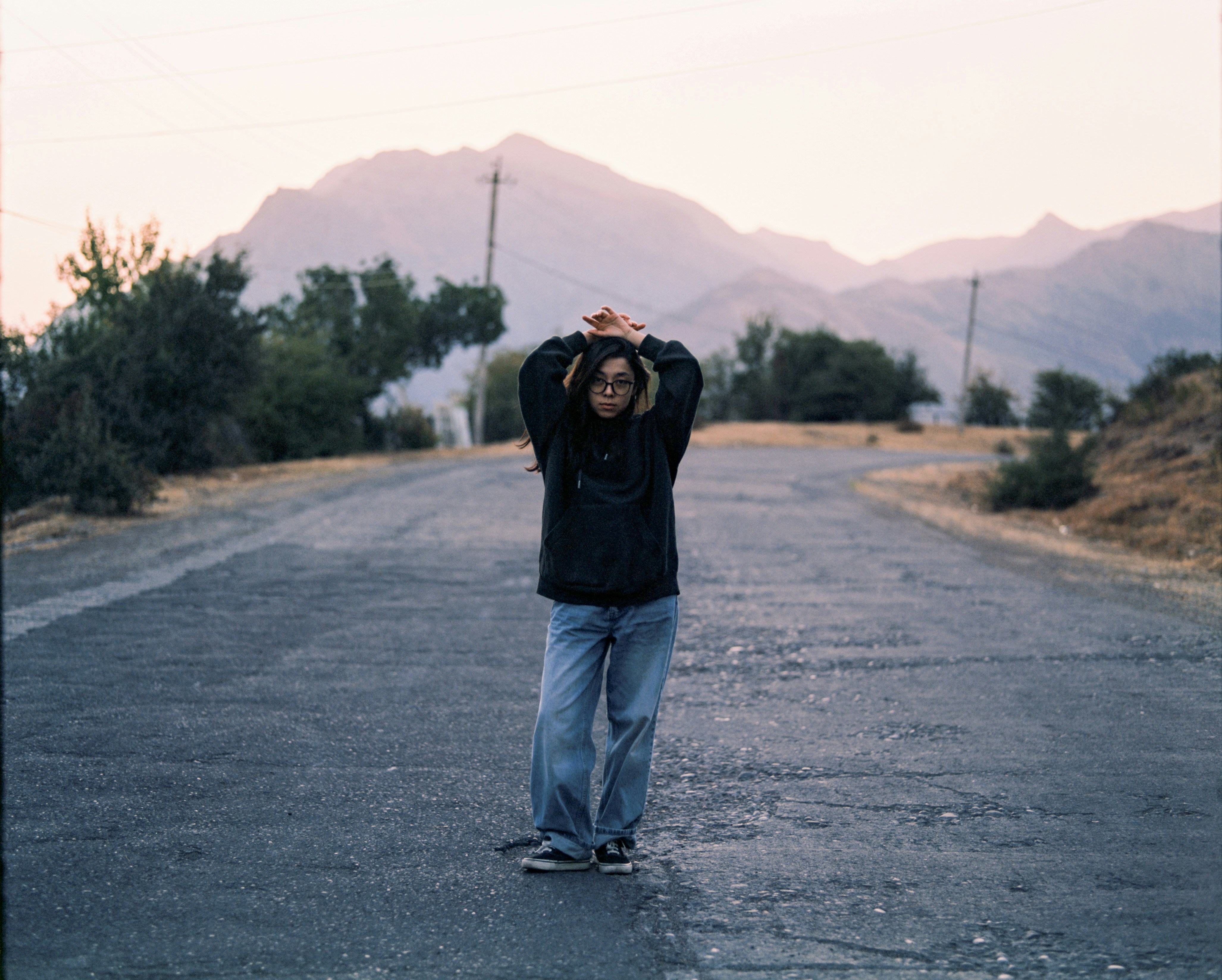 Person stands on a road with mountains behind.