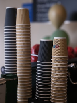 Stacks of disposable coffee cups in various colors.