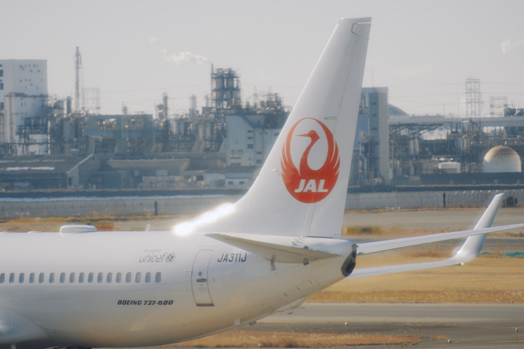 Japan airlines airplane tail with industrial background Via Unsplash (by Will Xiang)