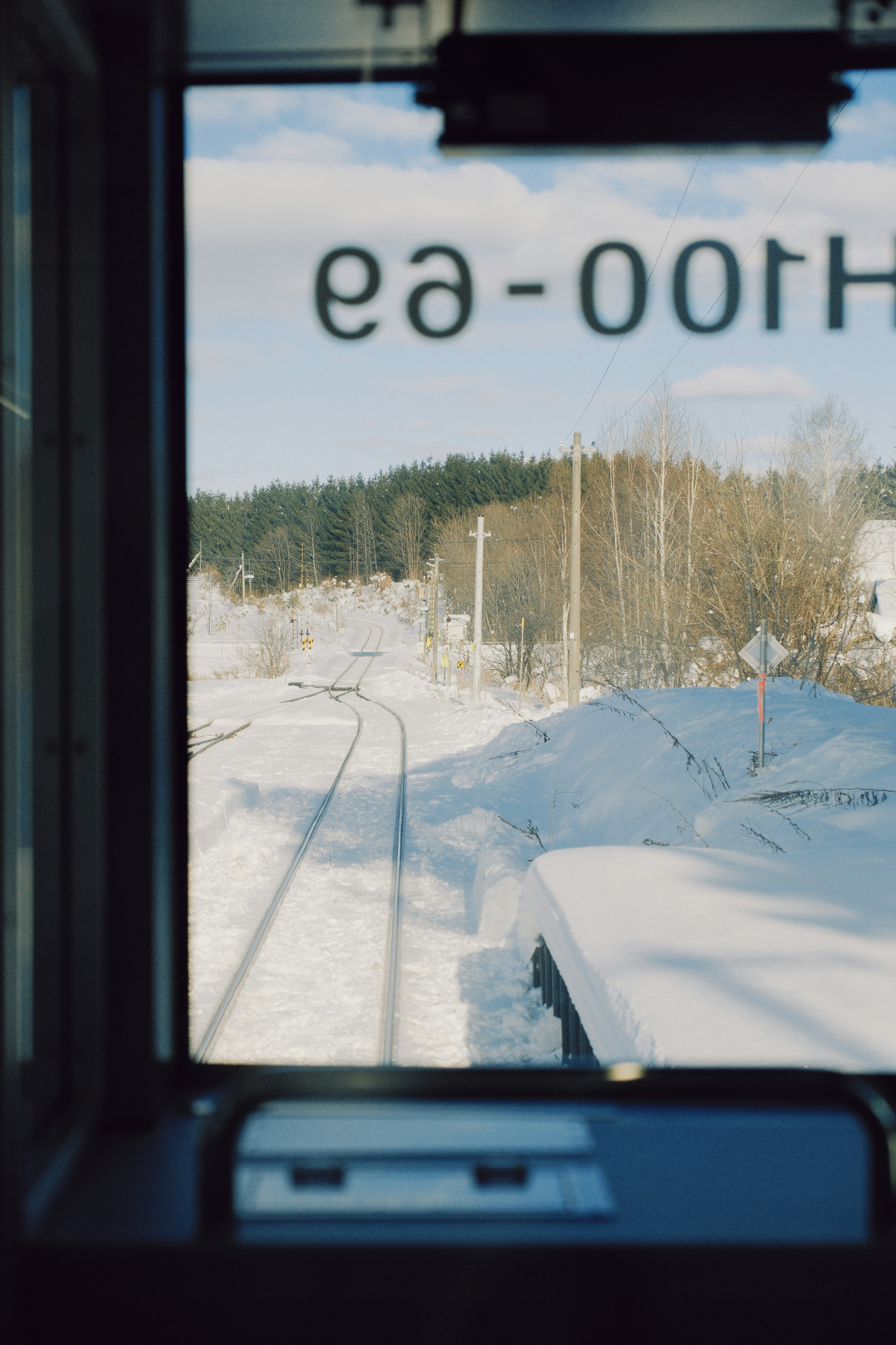 Snowy train tracks through a forest landscape