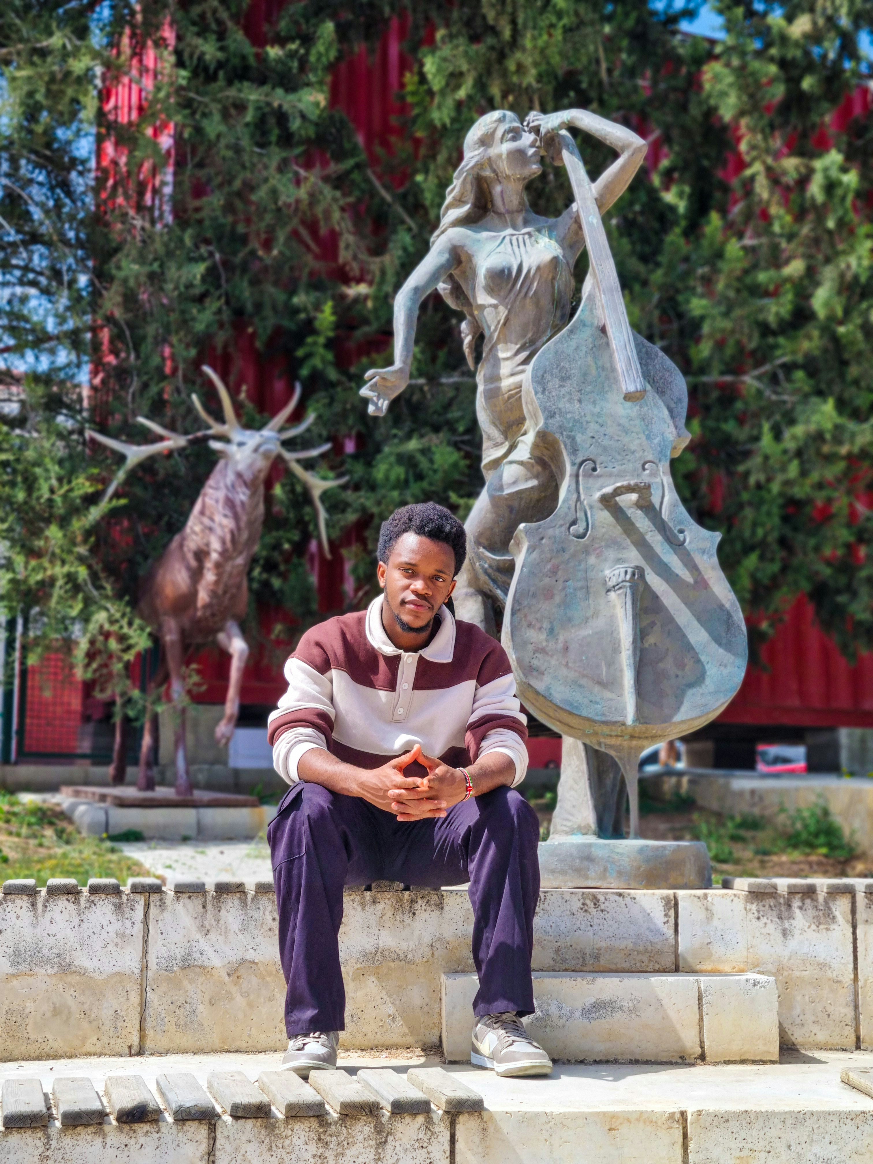 Man sitting near cello and deer sculptures