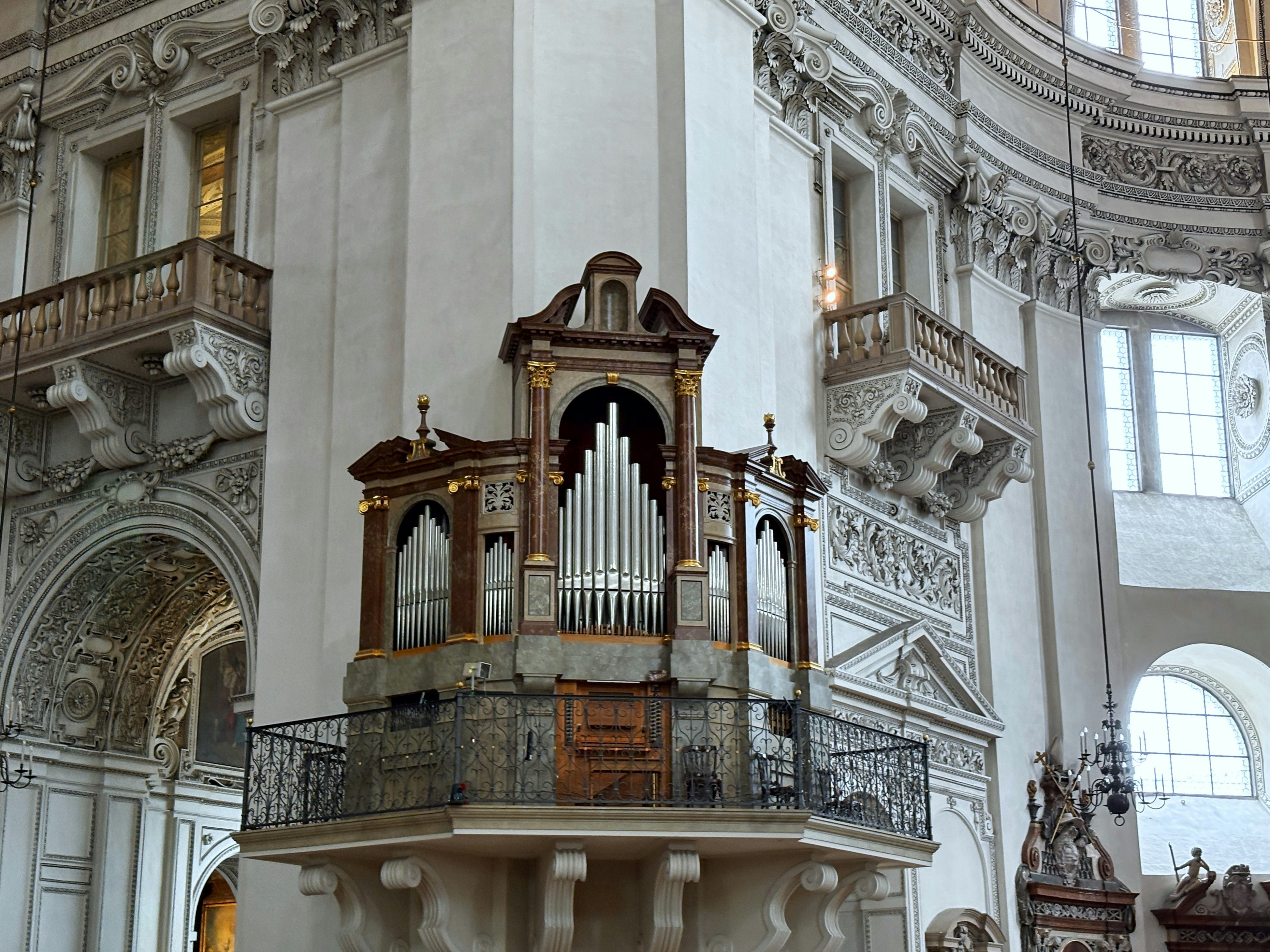 Pipe organ on a balcony inside a grand cathedral.