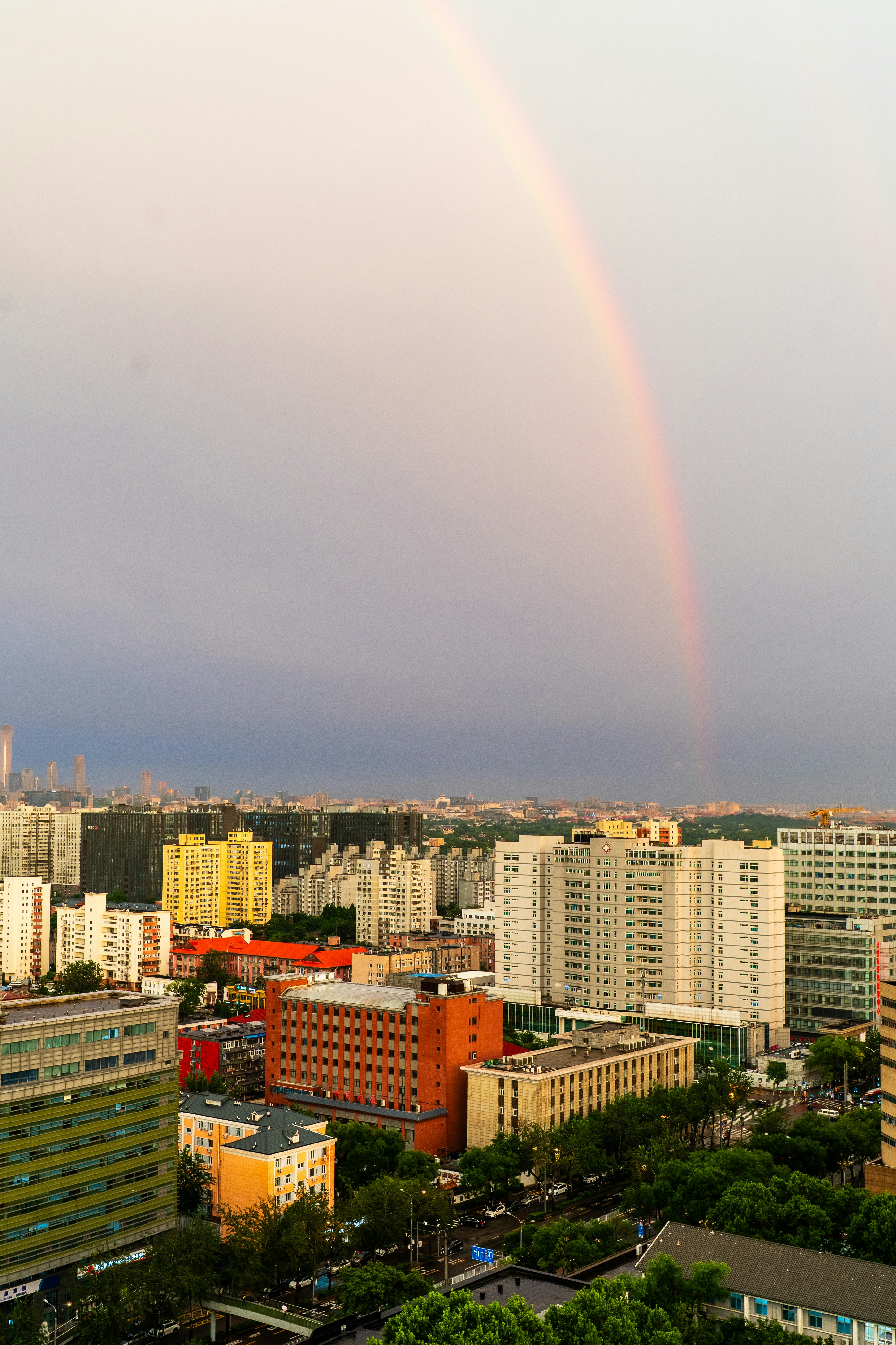 Rainbow arching over a city skyline at dusk
