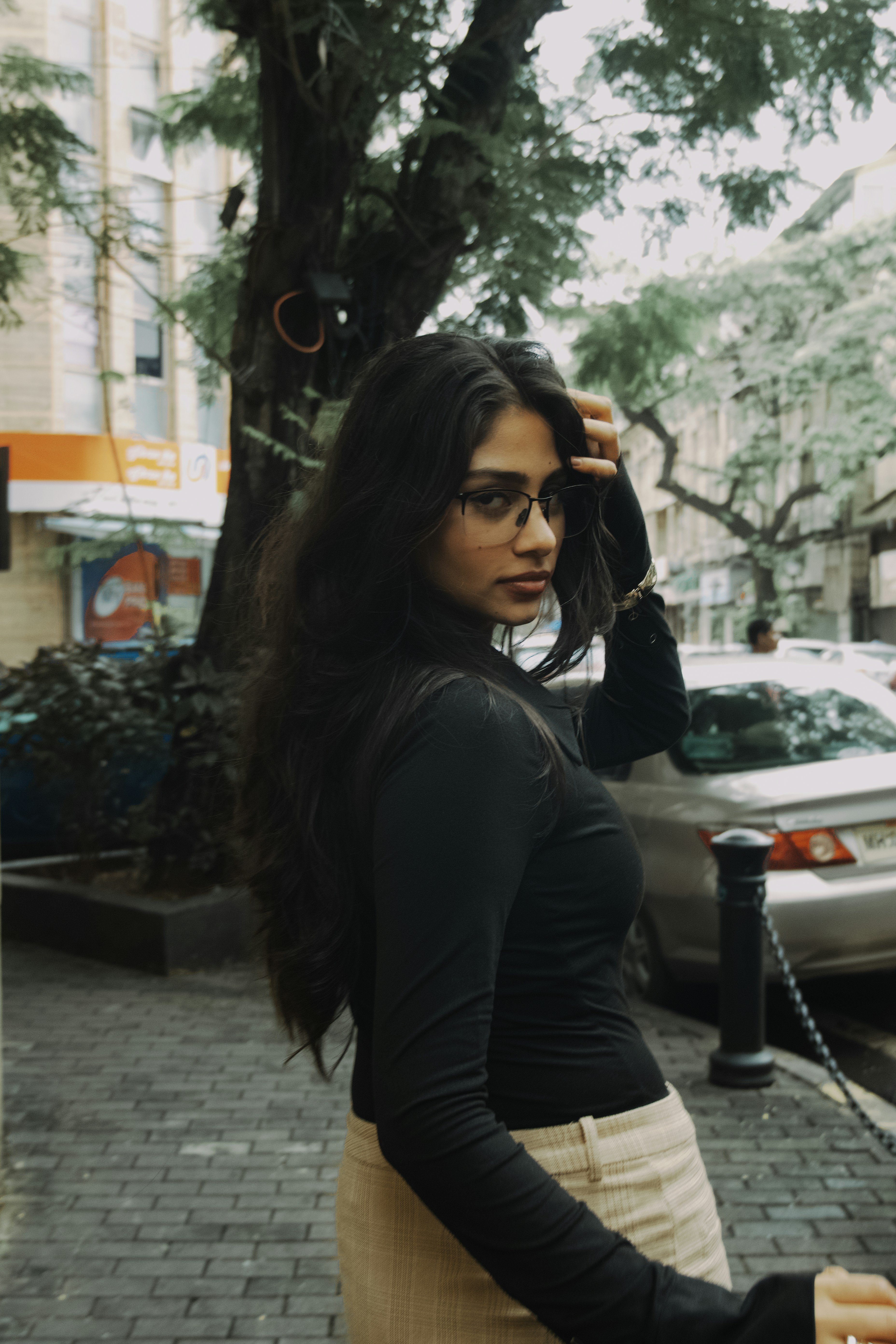 Frau mit langen dunklen Haaren trägt Brille im Freien