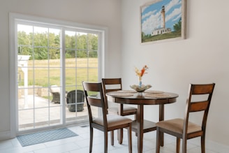 Round dining table with chairs and lighthouse painting.