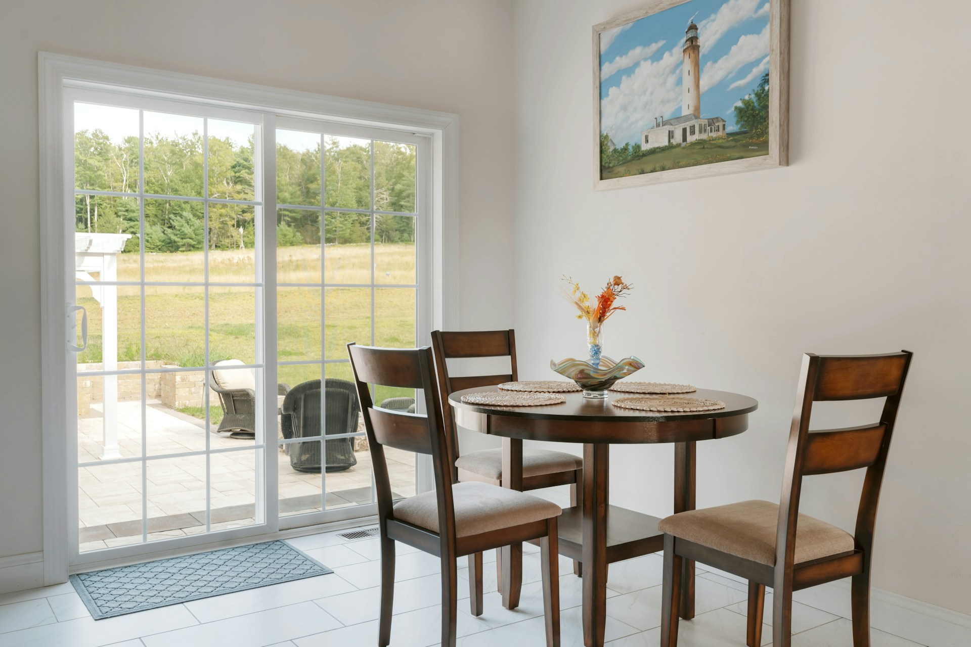 Round dining table with chairs and lighthouse painting.