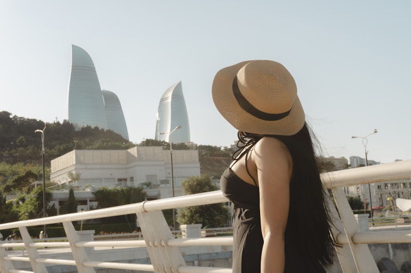 Woman in hat looks at flame towers in baku