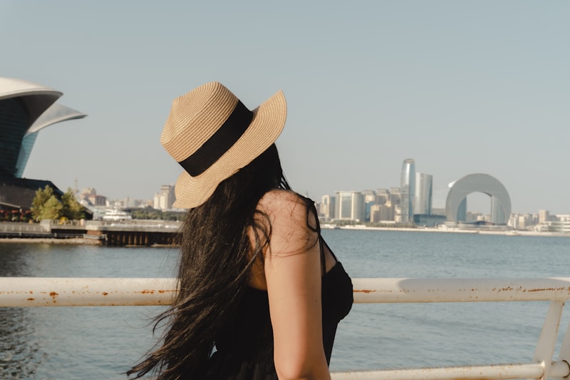 Woman in hat looking at cityscape by the water