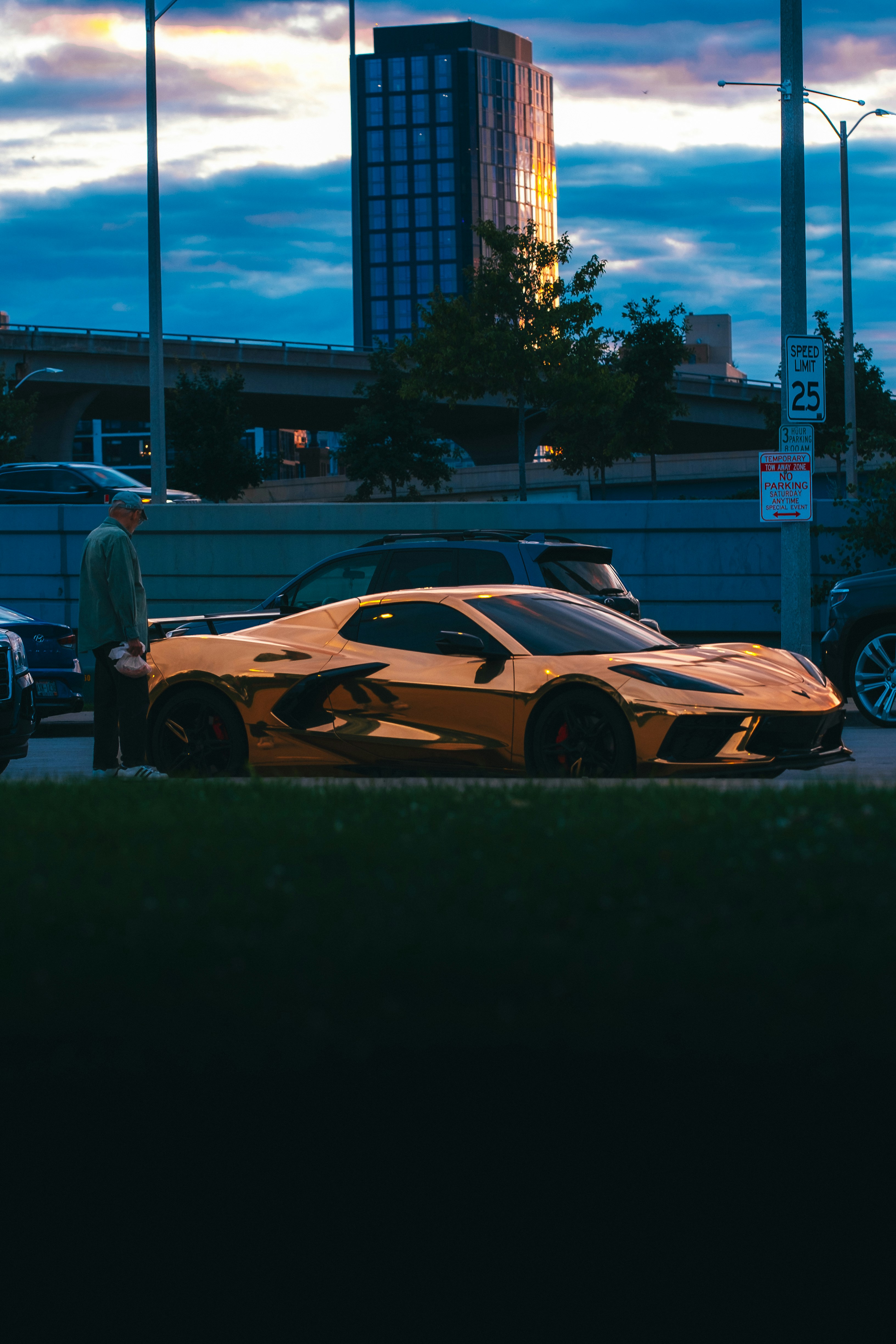 夕暮れ時に高層ビルの近くに停まっていた黄金のスポーツカー。