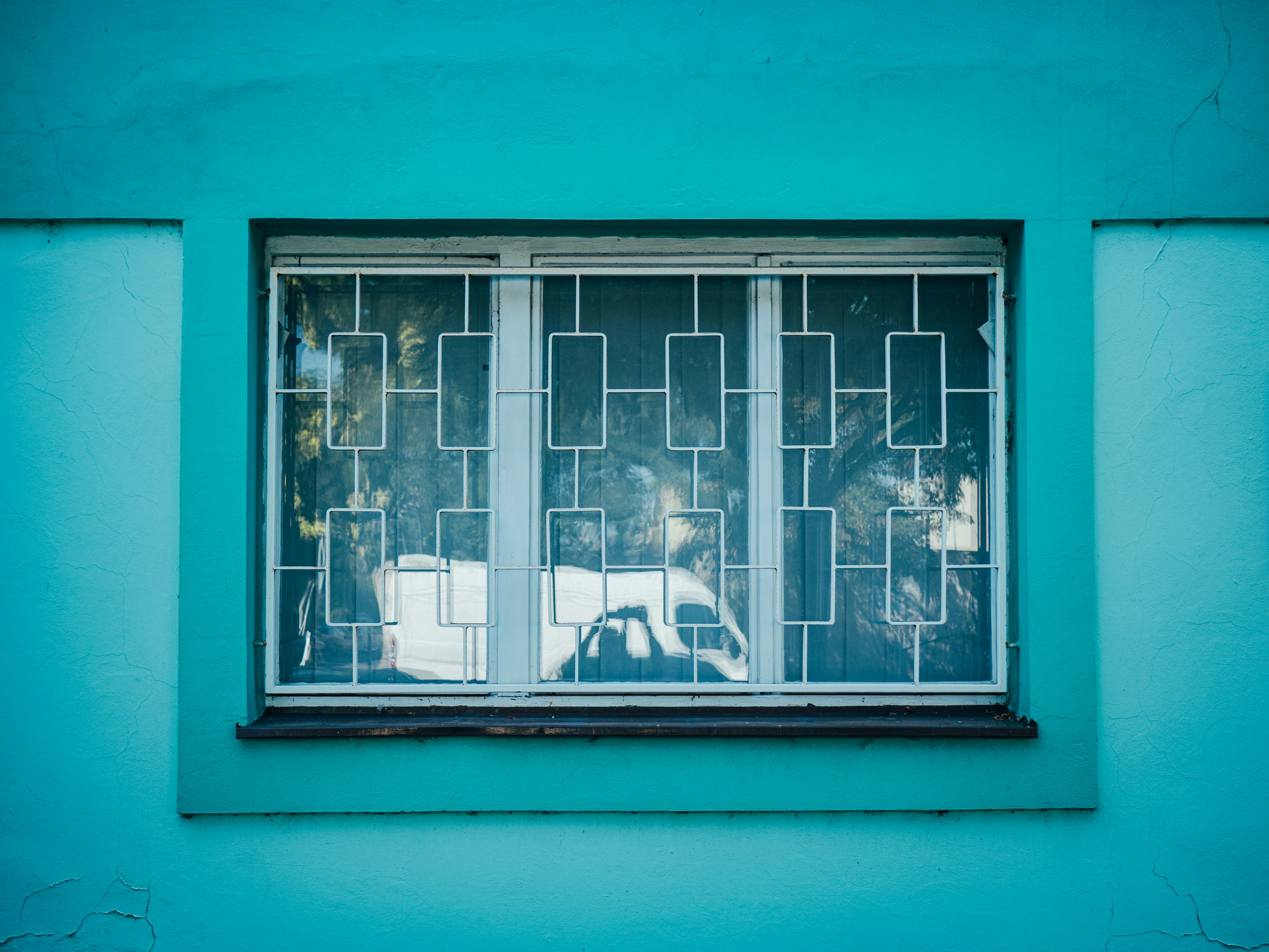 Window with white bars on a teal wall