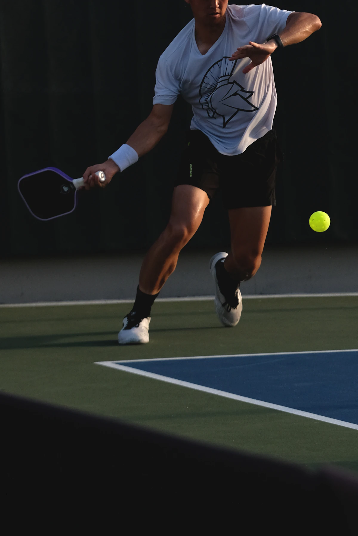 A pickleball player swinging a paddle mid-rally on an outdoor court