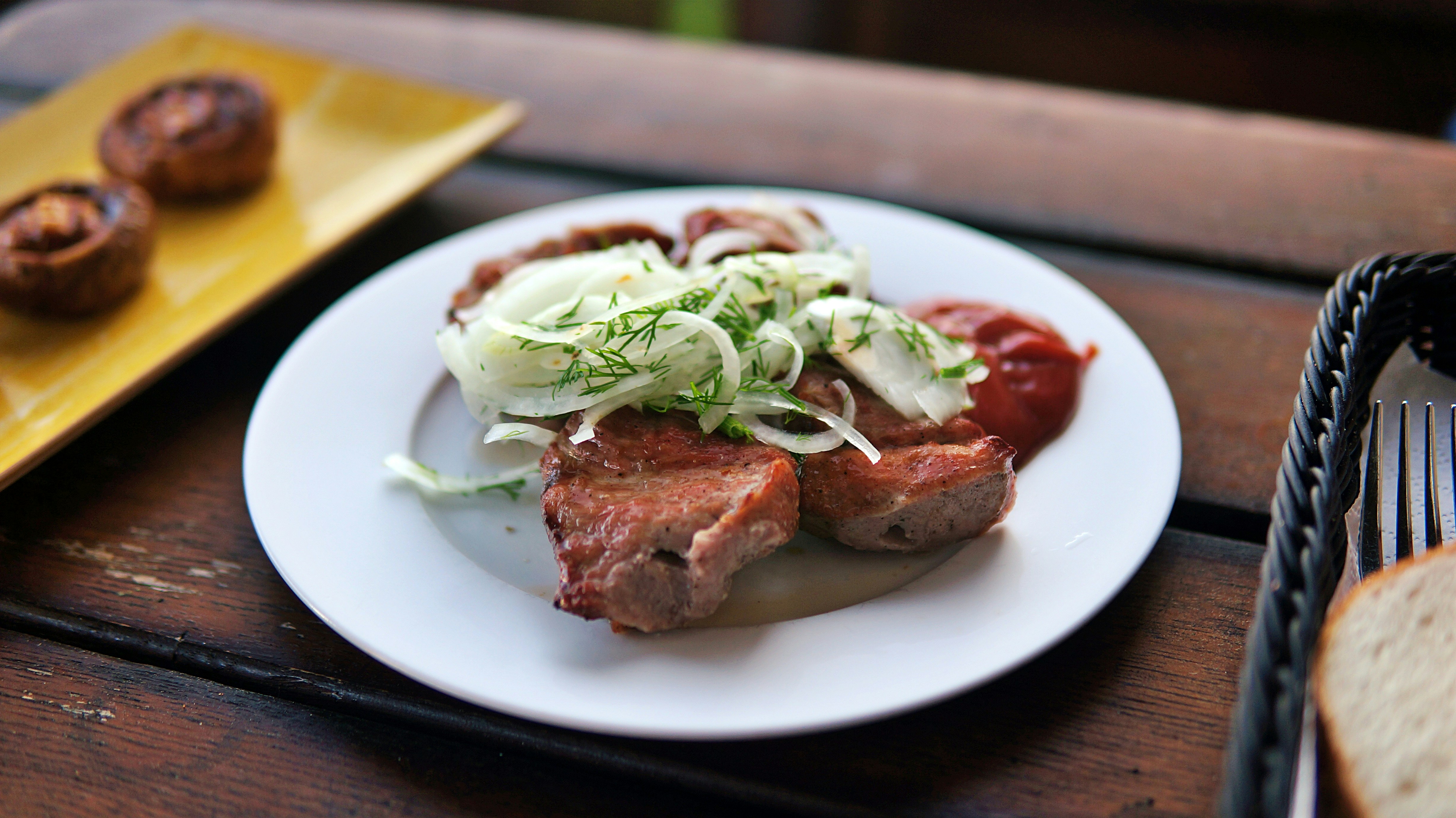 Grilled meat with onions and ketchup on plate