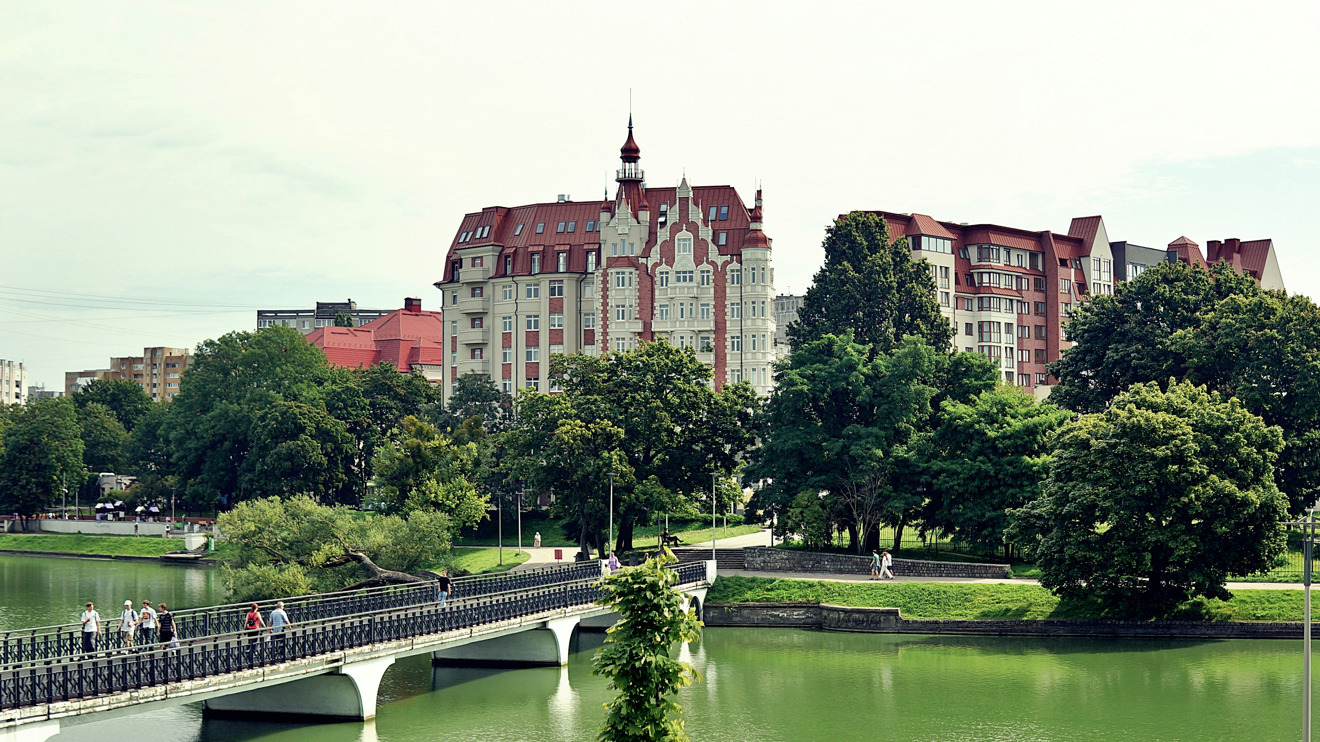Stadtpark mit einer Brücke über einen Fluss und Gebäuden.