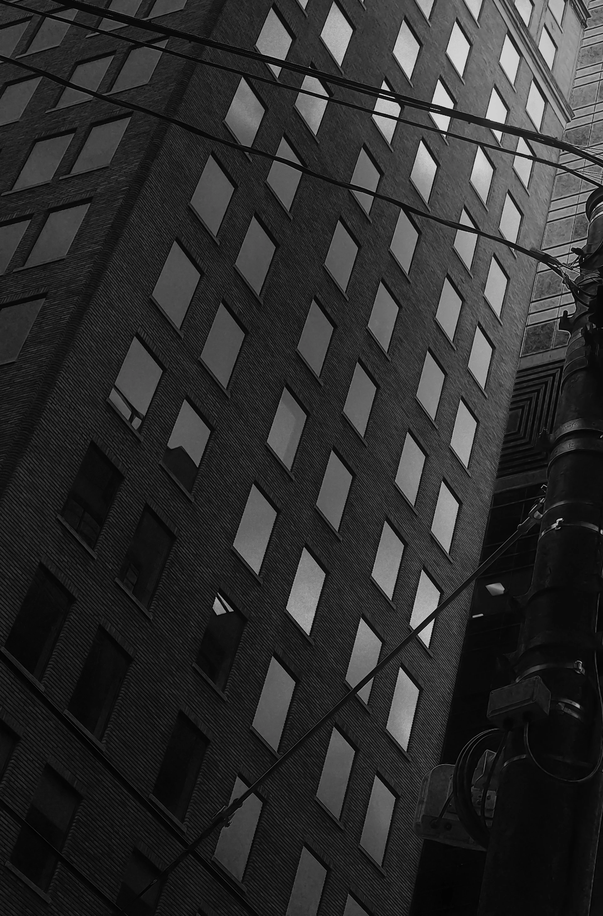 Tall brick building with many windows and wires.