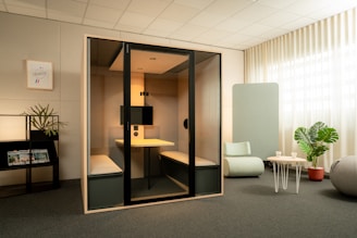 Modern office meeting pod with seating and desk.
