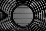 Close-up of a black circular grate with horizontal slats.