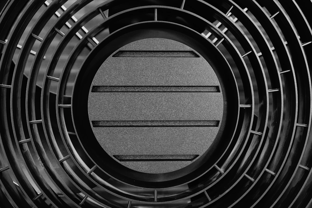 Close-up of a black circular heat pump grille with horizontal slats
